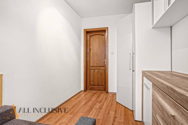 Interiér rodinného domu s podlahou s dřevěným dekorem a dřevěnými dveřmi.