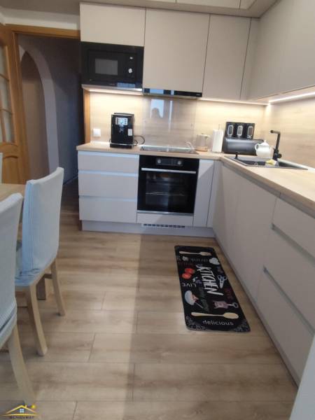 Kuchyně s podlahou s dřevěným dekorem v 3-pokojovém bytě, s moderním vybavením a dekorem.