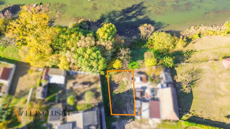 Letecký pohled na pozemek v Jahodné určený k bydlení, obklopený zelení blízko vody.