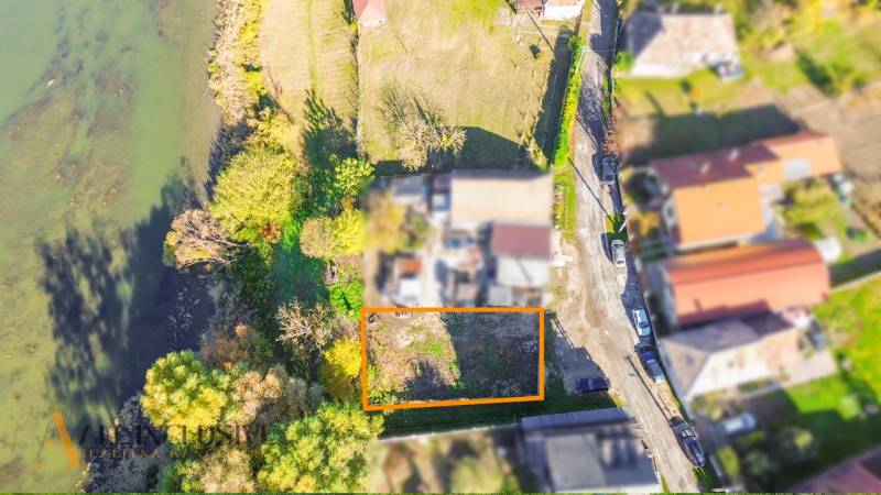 Letecký pohled na pozemky v Jahodné, obklopené zelení a vodní plochou.