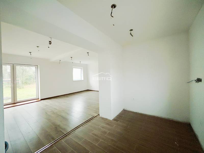 Interiér rodinného domu s podlahou s dřevěným dekorem a velkými okny do zahrady.