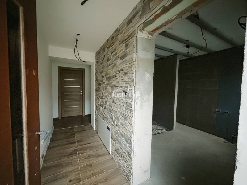 Chodba se stěnou s kamenným dekorem a podlahou s dřevěným dekorem v rodinném domě.