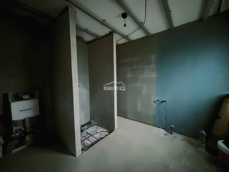 Interiér rodinného domu s nedokončenou koupelnou a instalacemi pro WC a umyvadlo.