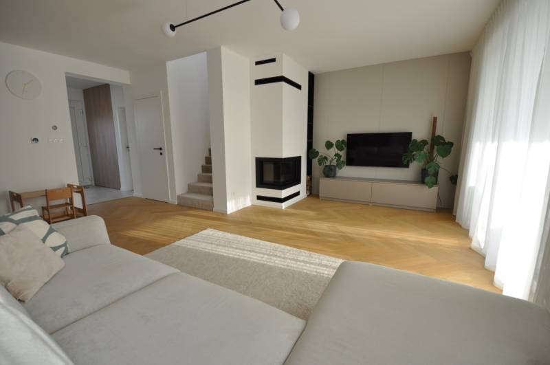 Obývací pokoj v rodinném domě s krbem a podlahou s dřevěným dekorem.