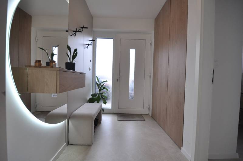 Vstupní hala v rodinném domě s velkým zrcadlem a úložnými prostory.