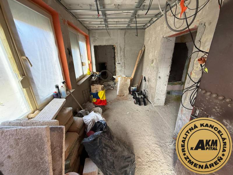 Pokoj v rodinném domě s rekonstrukcí. Stavební materiál, okna zakrytá fólií.