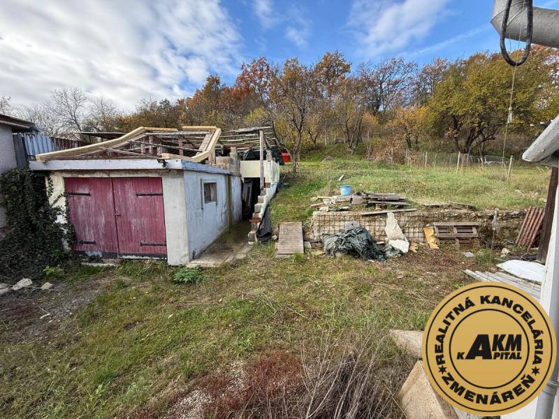 Rodinný dům ve Staré Kremničce s neudržovanou zahradou, starou garáží a dřevěnou konstrukcí.