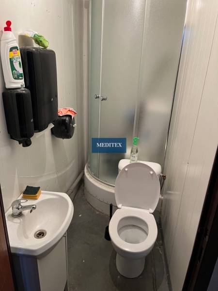 Malá koupelna se sprchovým koutem, umyvadlem a toaletou ve skladech a halách.