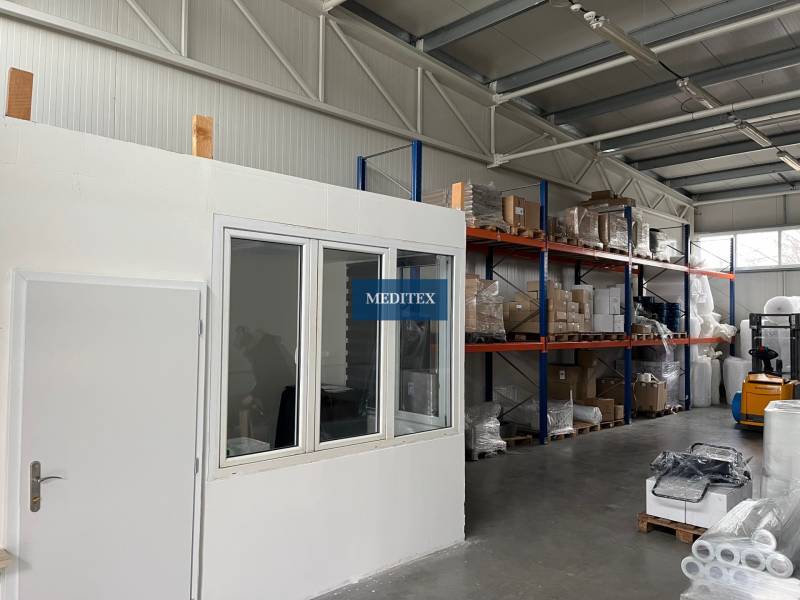 Sklady a haly s regály, zbožím a vysokozdvižným vozíkem.