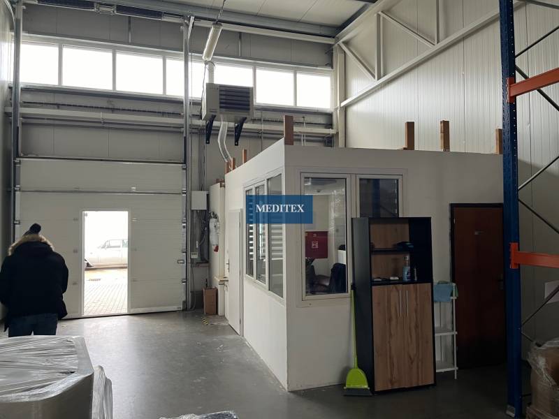 Interiér skladů a hal s přechodovou bránou a malou kanceláří nahoře.