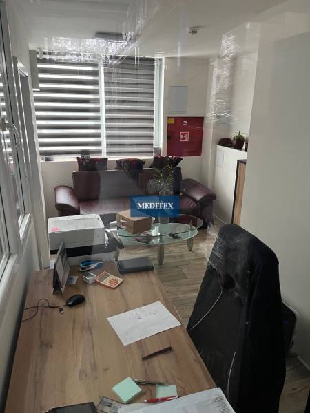 Kancelář ve skladech a halách s psacím stolem a podlahou s dřevěným dekorem.