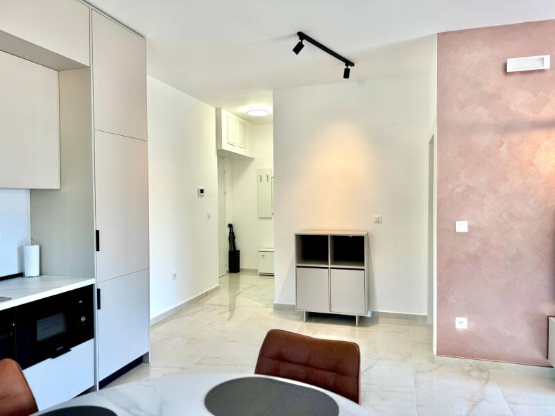 Interiér 1-pokojového bytu s kuchyňskou linkou, jídelním stolem a světlými stěnami.