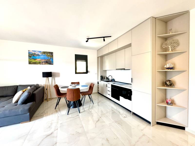 Světlá kuchyně s jídelním stolem a pohodlnou pohovkou v garsonce.