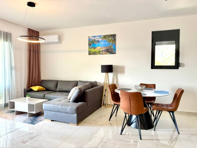 Obývací pokoj v 1-pokojovém bytě s podlahou s dřevěným dekorem, sedací soupravou a jídelním stolem.