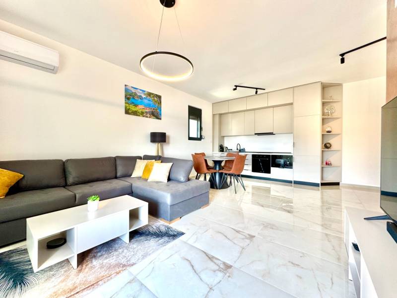 Interiér 1-pokojového bytu s pohovkou, kuchyňským koutem a jídelním stolem.