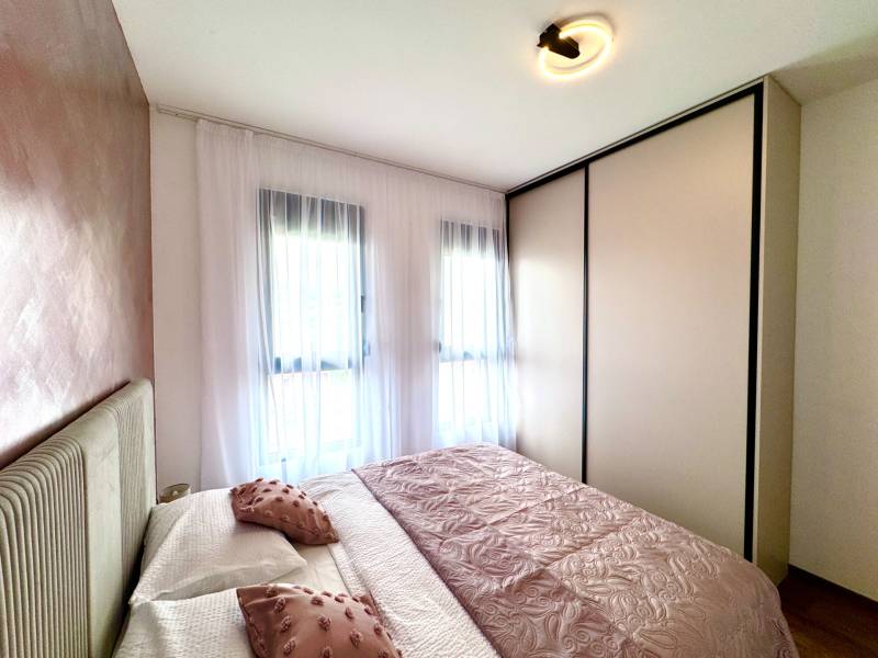 Pokoj se světlým nábytkem a dekoračními polštáři v jednopokojovém bytě.