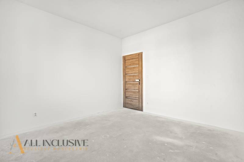 Prázdný pokoj v rodinném domě s bílými stěnami a dveřmi s dřevěným dekorem.