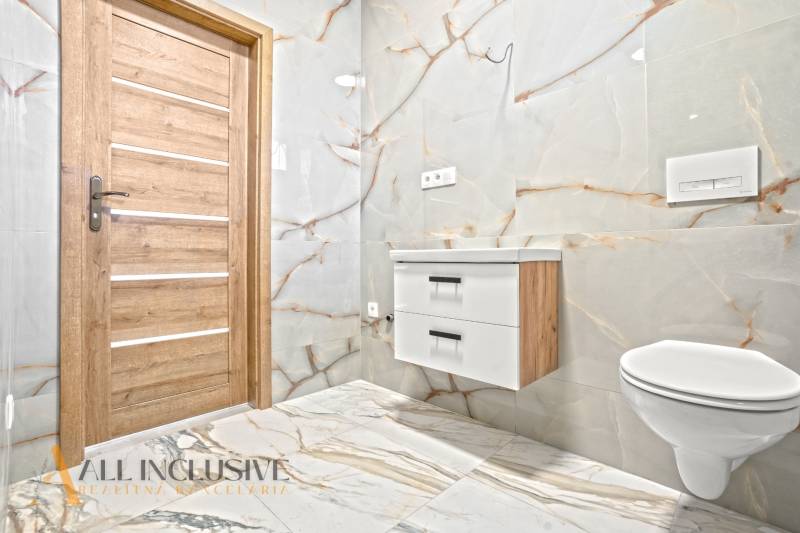 Koupelna v rodinném domě s obkladem a podlahou s mramorovým dekorem.