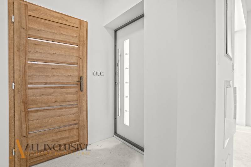 Interiér rodinného domu s dřevěným dekorem a jednoduchými bílými stěnami.