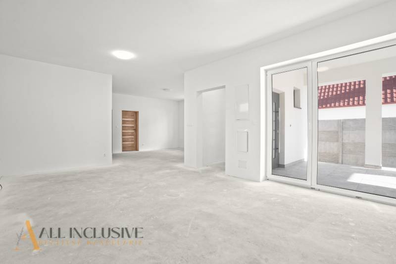 Prostorný interiér rodinného domu s bílými stěnami a velkými okny.