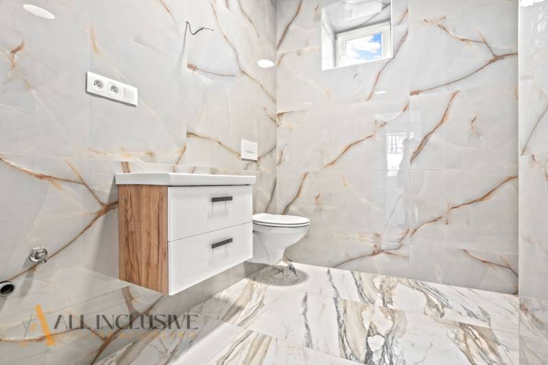 Koupelna v rodinném domě s keramickými obklady a nábytkem s dřevěným dekorem.