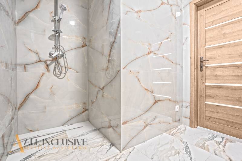 Koupelna v rodinném domě s imitací mramoru na stěnách a dřevěnými dveřmi.