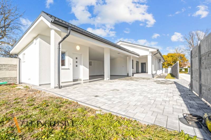 Rodinný dům v Orechové Potôni s bílou fasádou a dlážděným vstupem.