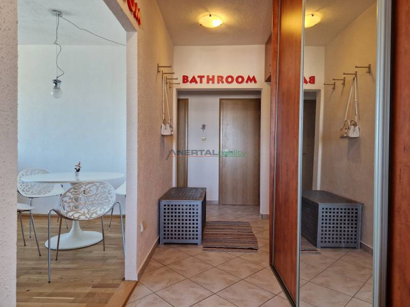 Chodba 3pokojového bytu s vestavěnými skříněmi a podlahou s dřevěným dekorem.