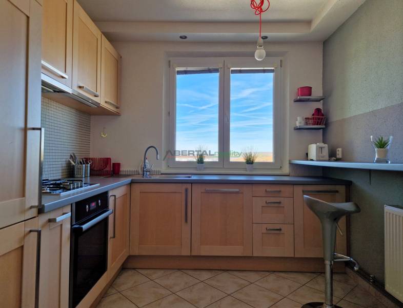 Kuchyně s oknem, podlaha s dřevěným dekorem, dlažba, zařízení ve 3pokojovém bytě.