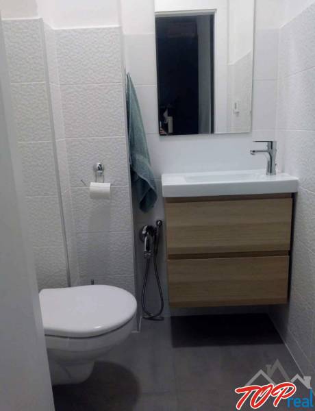 Kompaktní koupelna s umyvadlem a skříňkou v 1pokojovém bytě, obklady s jemnou texturou.