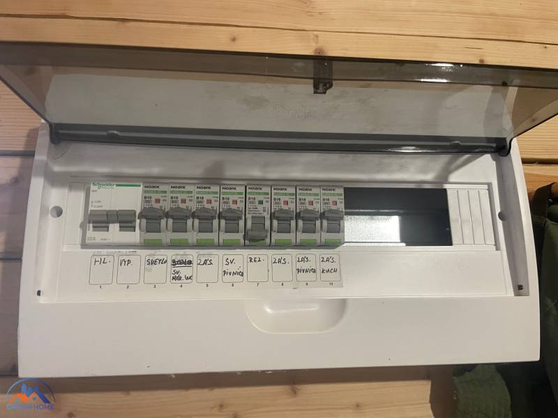 Elektrická rozvodná skříň v chatě s podlahou s dřevěným dekorem.