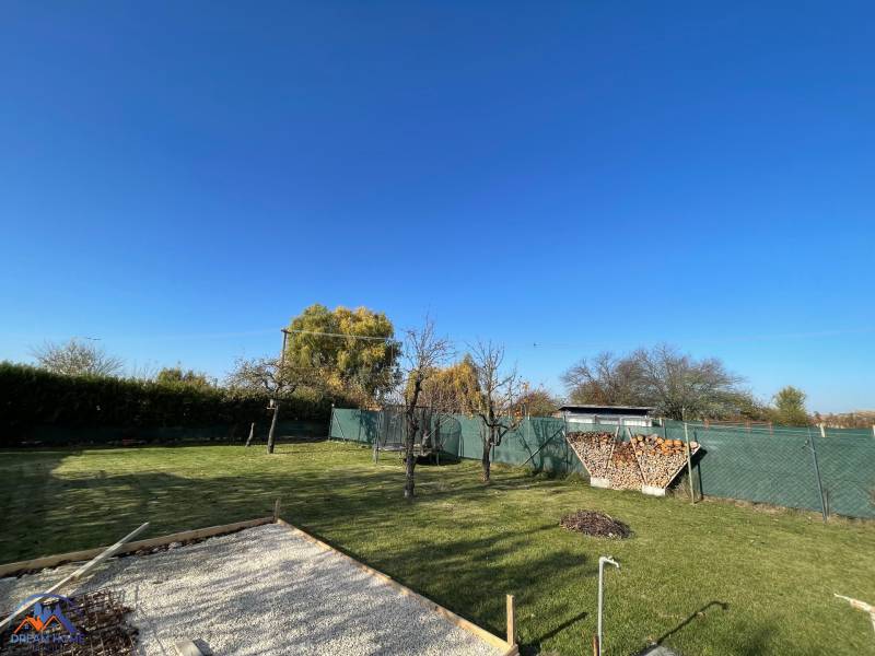 Zahrada u chaty na Nové osadě v Komárně s trávníkem a ohništěm.