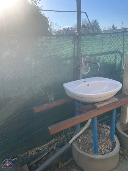 Umyvadlo u chaty na Nové osadě v Komárně, v exteriéru s ochrannou síťovinou.