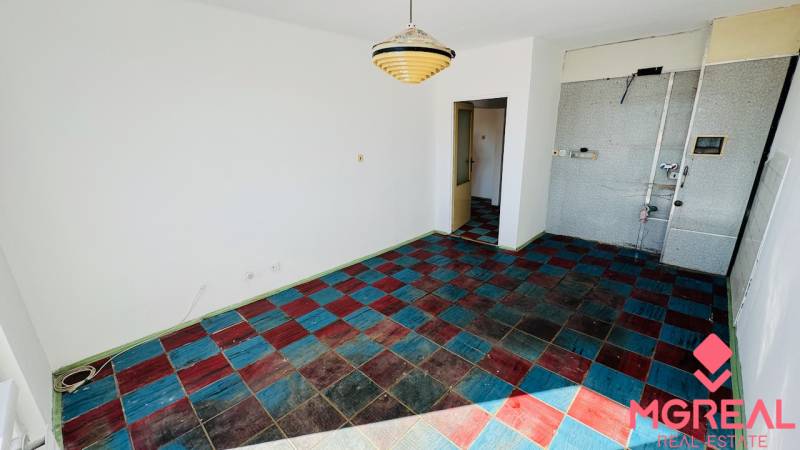 Pokoj v 1-pokojovém bytě s barevnou kachlovou podlahou a závěsným svítidlem.