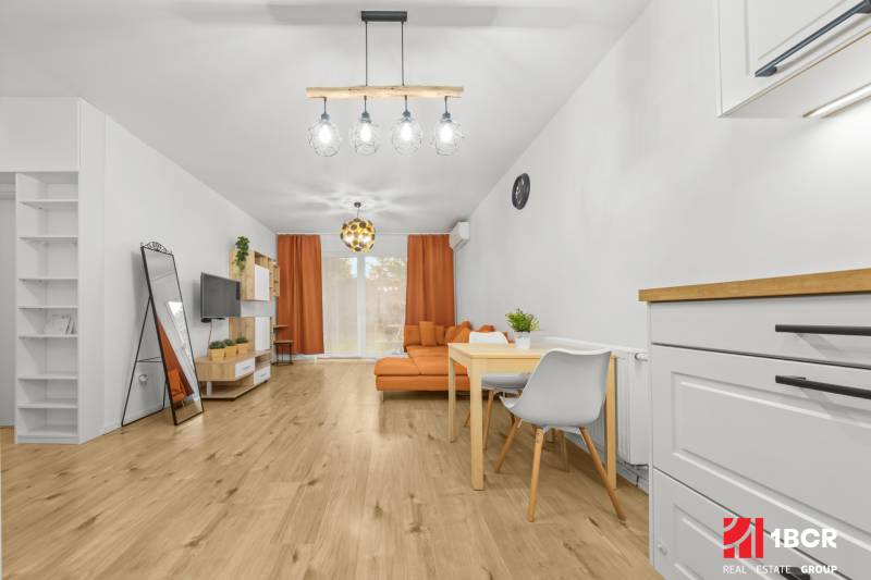 Obývací pokoj v 2-pokojovém bytě s podlahou s dřevěným dekorem a oranžovým nábytkem.