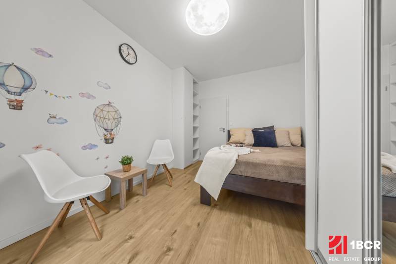 Ložnice v 2-pokojovém bytě s dekorem na stěně a podlahou s dřevěným dekorem.