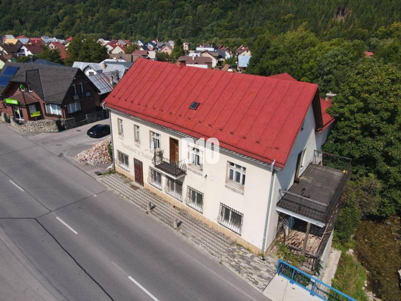 Budova v Belej s červenou střechou, okolní domy a příroda.