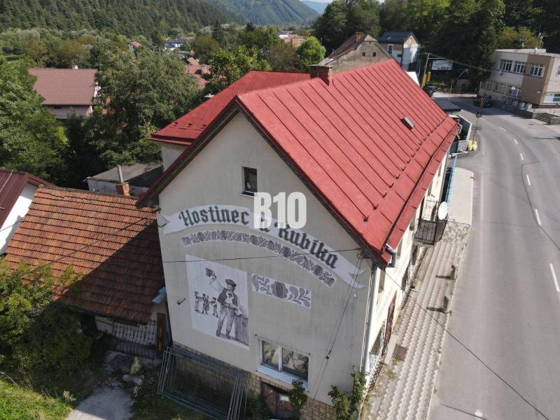 Budova hostince v Belej s červenou střechou a vyobrazením na stěně.