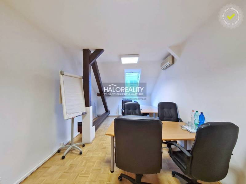 Kanceláře s podlahou s dřevěným dekorem, stůl, židle, flipchart, voda na stole.