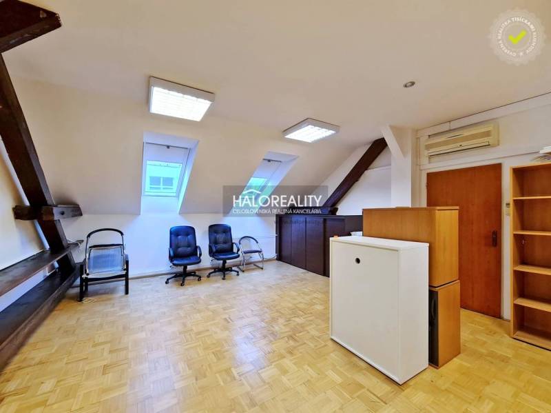 Kanceláře s podlahou s dřevěným dekorem, křesly a okny v podkrovní místnosti.