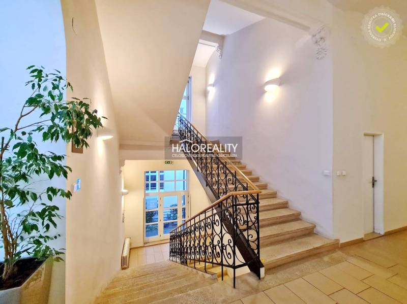 Světlé schodiště s ozdobným zábradlím, vedoucí do kanceláří.