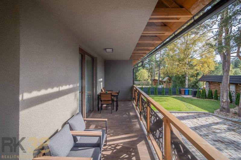 Balkon 2-pokojového bytu v Tatranské Lomnici s podlahou s dřevěným dekorem a zahradním nábytkem.