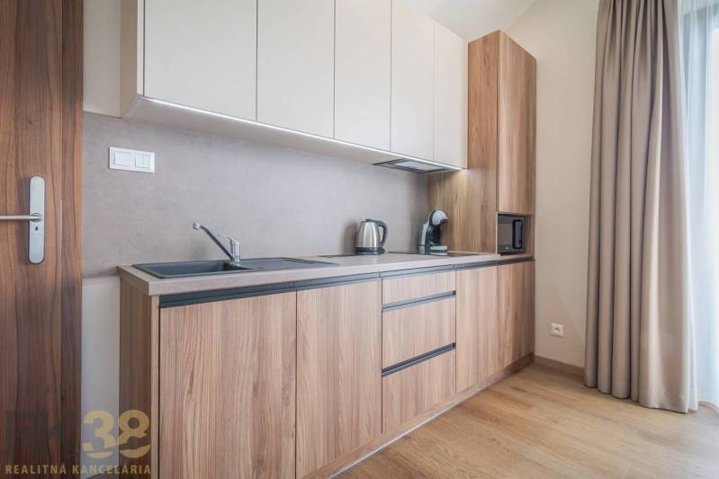 Kuchyně v 2-pokojovém bytě s podlahou s dřevěným dekorem a světlou linkou.