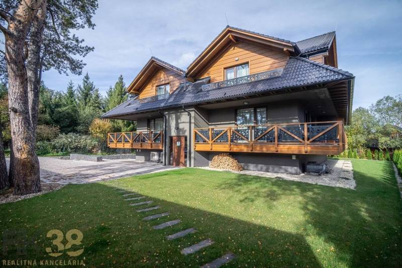 Dvoupatrový dům s dřevěnými prvky a zeleným trávníkem v Tatranské Lomnici.