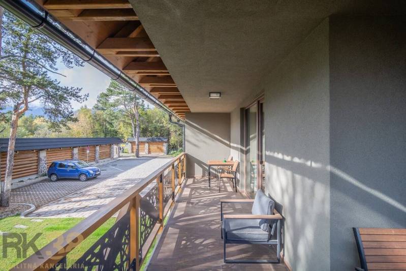 Balkon 2-pokojového bytu v Tatranské Lomnici s dřevěným dekorem a venkovním posezením.