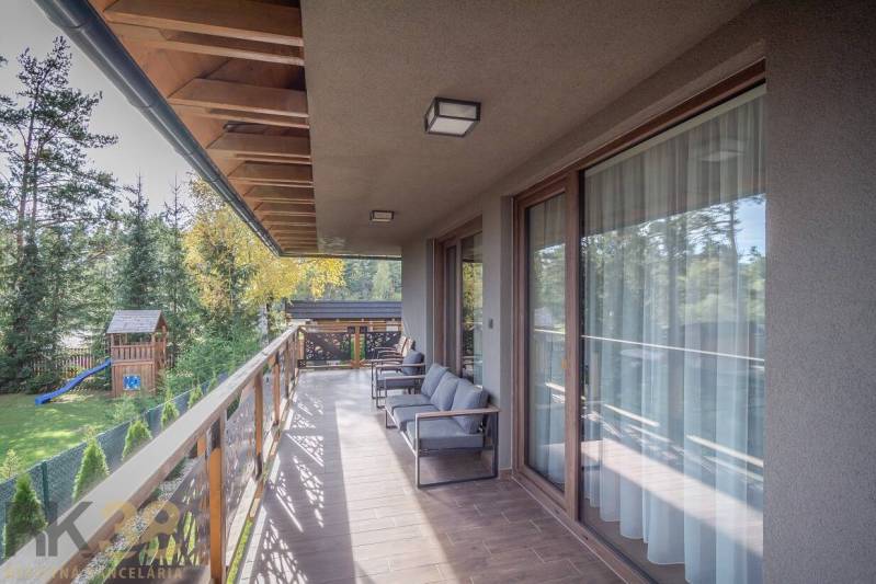 Balkon 2pokojového bytu v Tatranské Lomnici s podlahou s dřevěným dekorem a výhledem na zeleň.