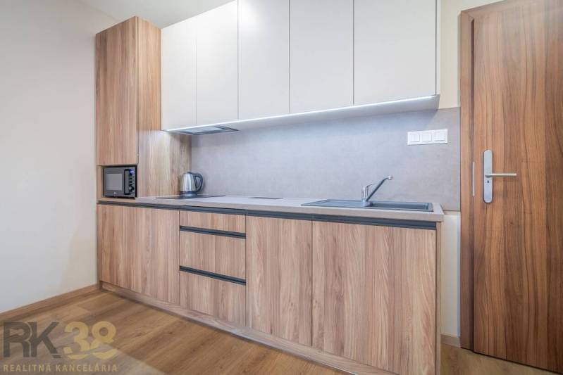 Kuchyňská linka s dřevěným dekorem, vestavěné spotřebiče a podlaha s dřevěným dekorem v 2-pokojovém bytě.