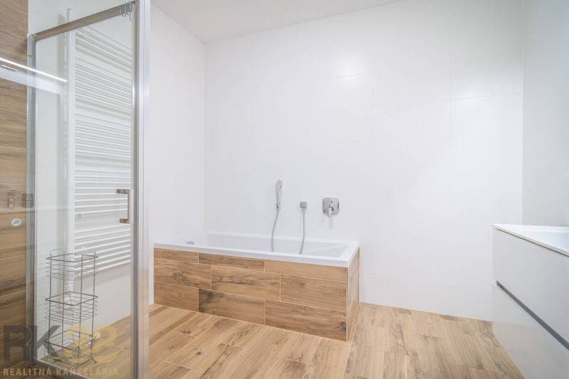 Koupelna s vanou a podlahou s dřevěným dekorem v 2-pokojovém bytě.