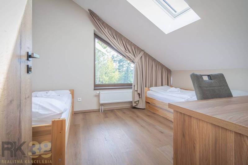 Ložnice v dvoupokojovém bytě s dvěma postelemi a podlahou s dřevěným dekorem.