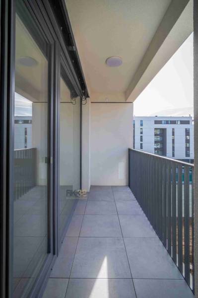 Balkon 2-pokojového bytu v Popradu s dlažbou a výhledem na moderní budovy.